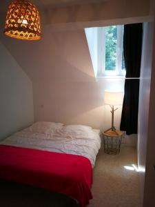 1 dormitorio con 1 cama con manta roja y ventana en Résidence le 09 en Uzerche