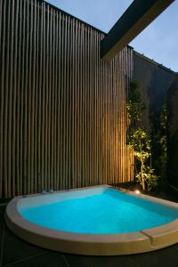 a swimming pool in front of a wooden wall at The Meibia Miyazaki in Miyazaki