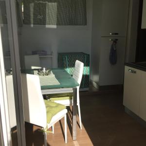 cocina con mesa verde y sillas blancas en Apartment Salivoli, en Piombino