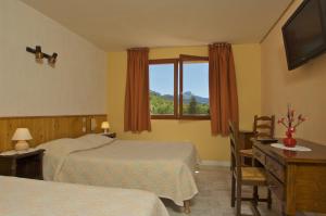 a bedroom with two beds and a desk and a window at Boustigue Hotel in Corps