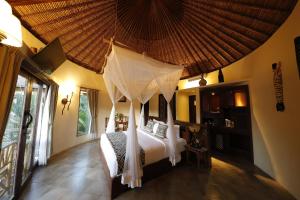 a bedroom with a bed with a canopy at Mara River Safari Lodge Bali in Keramas