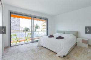 a white bedroom with a bed and a large window at Modern Croisette & Palm Beach in Cannes