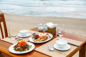 a wooden table with two plates of food and wine glasses at Lazi Beach Resort in Lagi