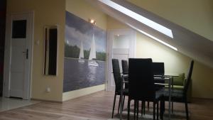 une salle à manger avec une table, des chaises et un tableau dans l'établissement Apartament Relax, à Giżycko