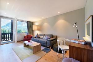 ein Wohnzimmer mit einem Sofa und einem Tisch in der Unterkunft Hotel Seehof-Arosa in Arosa
