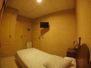 a bedroom with a bed and a tv on the wall at Hostal La Casa de Enfrente in Málaga