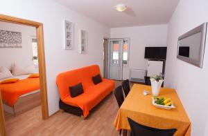 a living room with an orange chair and a table at Apartments Lucia in Podstrana