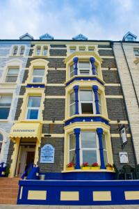 un grande edificio con finiture blu e gialle di Queensbridge Hotel ad Aberystwyth