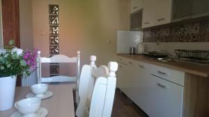 a kitchen with white cabinets and a table with flowers at Apartament Lawenda in Łeba