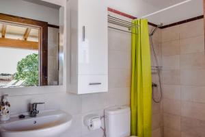 a bathroom with a sink and a yellow shower curtain at Finca Sa Torre de'n Piza - Grupo Berna in Campos +25 photos