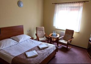 a bedroom with a bed and two chairs and a table at Hotel Omega in Ostrów Wielkopolski
