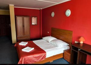 オストルフ・ビエルコポルスキにあるHotel Omegaの赤いベッドルーム(ベッド1台、タオル2枚付)
