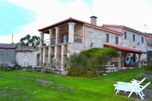 una gran casa de piedra con una mesa de picnic delante de ella en Alojamiento Pazos, en Cea