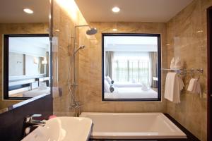 ein Badezimmer mit einer Badewanne, einem Waschbecken und einem Spiegel in der Unterkunft RK Riverside Resort & Spa (Reon Kruewal) in Ban Khlong Krang