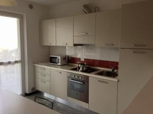 a kitchen with white cabinets and a sink and a microwave at Casa Lampone in Trento