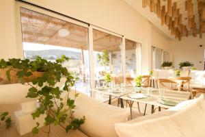 um restaurante com mesas e cadeiras brancas e uma grande janela em Aelia Wellness Retreat em Nicósia