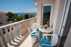 a balcony with a table and chairs with a view of the ocean at Apartments Lucia in Podstrana