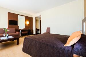 アルカニスにあるHotel Ciudad de Alcañizのベッドとリビングルームが備わるホテルルームです。