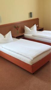 two beds in a hotel room with white sheets at Gasthof Hirsch Betzigau in Betzigau