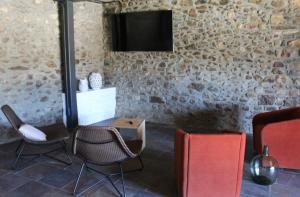 Habitación con sillas y TV en una pared de piedra. en Mas Ravetllat, en Isóbol