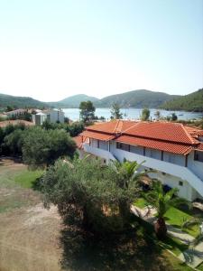 a white building with a red roof and trees at The Port in Porto Koufo