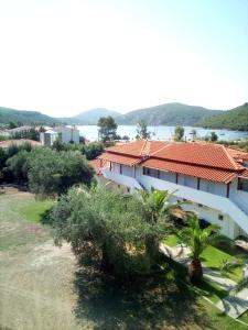 a white building with a red roof and some trees at The Port in Porto Koufo