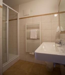 een witte badkamer met een wastafel en een douche bij Hotel Hohe Tauern in Matrei in Osttirol