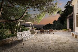 een schommel op een patio met een zonsondergang op de achtergrond bij Koukounari luxury villa in Chania
