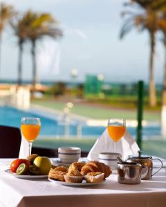 - une table avec de la nourriture et deux verres de jus d'orange dans l'établissement Evenia Zoraida Garden, à Roquetas de Mar
