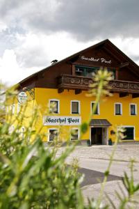 ein großes gelbes Gebäude mit einem Schild drauf in der Unterkunft Gasthof Post in Peilstein im Mühlviertel