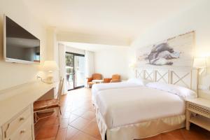 a hotel room with two beds and a television at Iberostar Selection Andalucia Playa in Chiclana de la Frontera