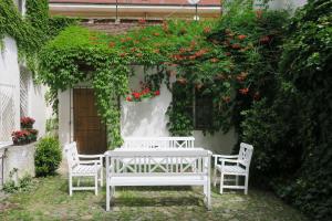 une table et des chaises blanches dans un jardin fleuri dans l'établissement Apartments near Lesser Town, à Prague
