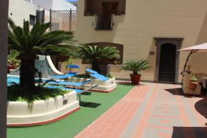 un complexe avec une piscine bordée de palmiers et de toboggans dans l'établissement Hotel La Filadelfia, à Lipari