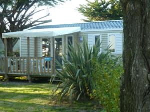 a white mobile home with a porch and a deck at Camping Les Perouses in Saint-Clément-des-Baleines