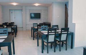 a dining room with tables and chairs and a flat screen tv at Hotel City in Koszalin