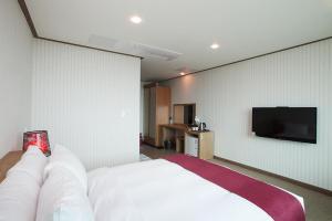 Habitación de hotel con cama y TV de pantalla plana. en Hotel California, en Seogwipo