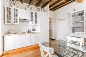 a kitchen with white cabinets and a glass table at Navona Bernini Lodge in Rome