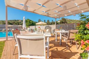 un patio con tavolo e sedie sotto un pergolato di Dimitra & Evdokia Hotel ad Agia Marina Nea Kydonias Altre 145 foto