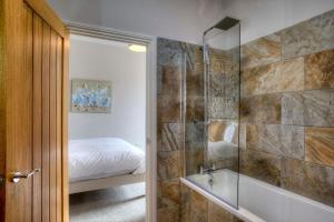 a bathroom with a shower and a bed and a tub at Bertram's in Warkworth