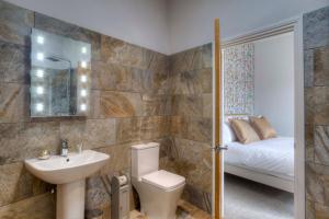 a bathroom with a sink and a toilet and a bed at Bertram's in Warkworth