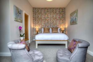 a bedroom with a bed and two chairs at Bertram's in Warkworth
