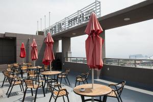 a row of tables and chairs with red umbrellas on a roof at Hotel California in Seogwipo