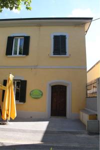 a yellow building with a door and a closed umbrella at Il Viale b&b in Pontedera