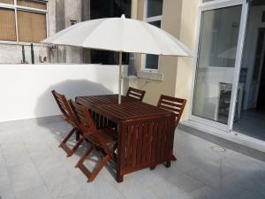 una mesa de madera con sillas y una sombrilla en el balcón en Casa dos Azulejos, en Lisboa