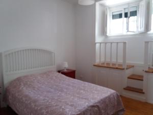 a white bedroom with a bed and a window at Casa dos Azulejos in Lisbon