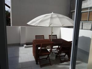 a wooden table with chairs and an umbrella on a patio at Casa dos Azulejos in Lisbon