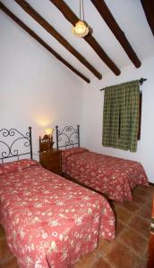 a bedroom with two beds and a ceiling at Casa Rural Casa Ronda in El Bosque