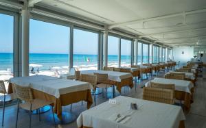 a restaurant with white tables and chairs and the ocean at Hotel Amyclae in Sperlonga
