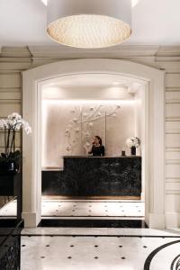 une femme prenant une photo d'un miroir dans une salle de bains dans l'établissement Le Narcisse Blanc, à Paris