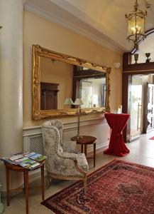 a living room with a chair and a mirror at Stadthotel Herzog Ludwig in Landshut